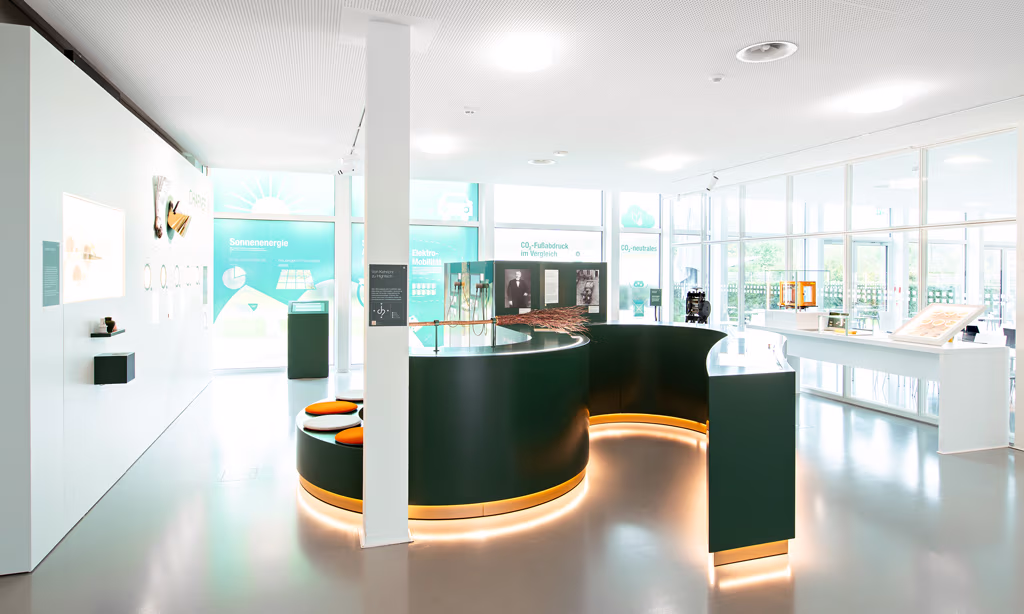 Lichtdurchflutetes Foyer mit grünem geschwungenen Tresen in der Mitte des Raums.