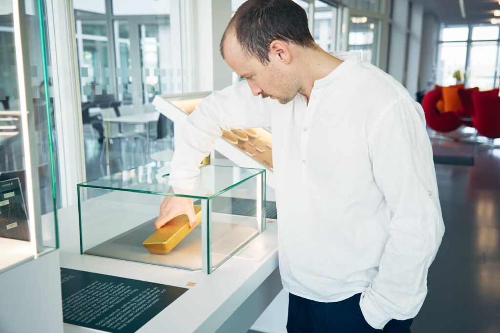 Ein Mann in der Ausstellung nimmt einen Goldbarren aus einer Glasvitrine.