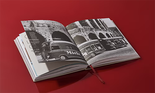 Das Miele Buch liegt aufgeklappt auf rotem Hintergrund.