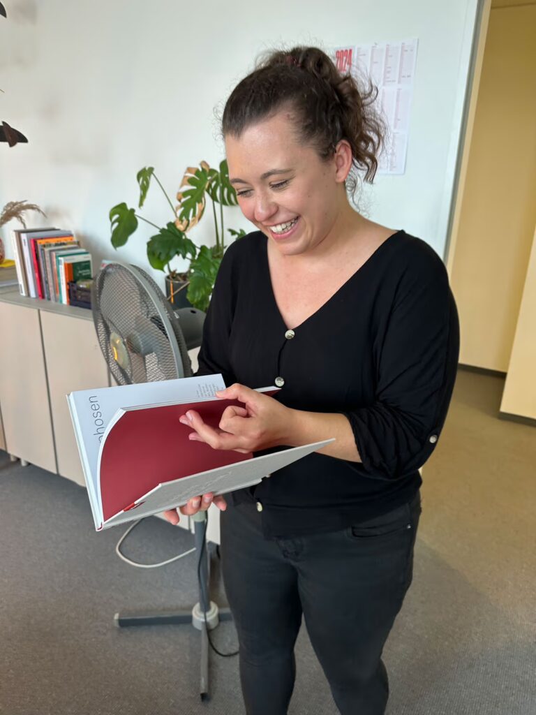 Mitarbeiterin von bup blättert in einem druckfrischen Miele Buch und freut sich sehr.