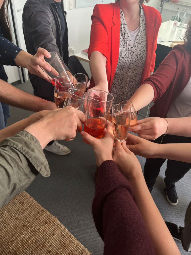 Elf Hände stoßen mit Sekt- und Saftgläsern an.