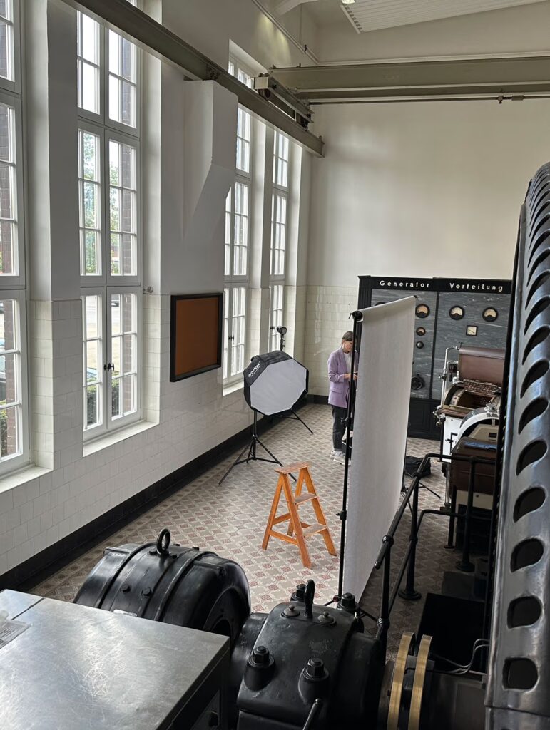 Ein Shooting-Setup in einer alten Werkshalle mit Mosaikfußboden und hohen Sprossenfenstern. Alte Geräte oder Generatoren sind zu sehen.