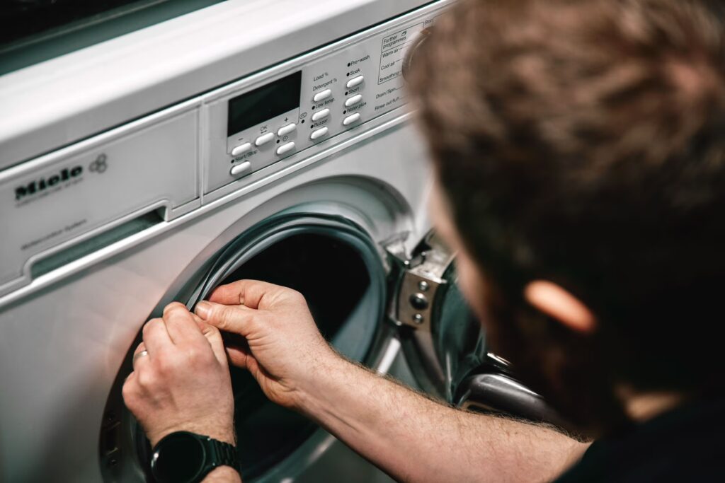 Miele Waschmaschine mit offener Tür. Ein Mann prüft mit den Händen die Gummidichtung.